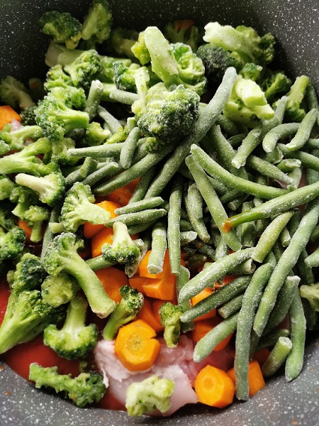 Gefrorene Broccoli und Grüne Bohnen im Topf mit Tomatensoße und Karotten