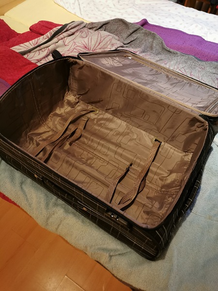 Leere braune Koffer am Bett