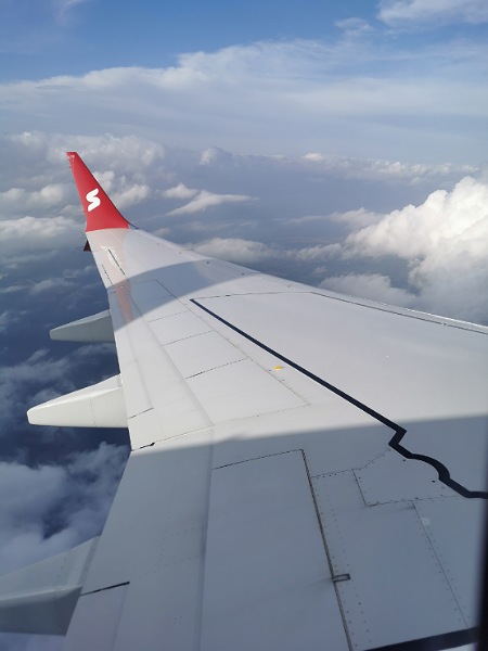 Foto aus dem Flugzeug mit dem Flügel und Wolken