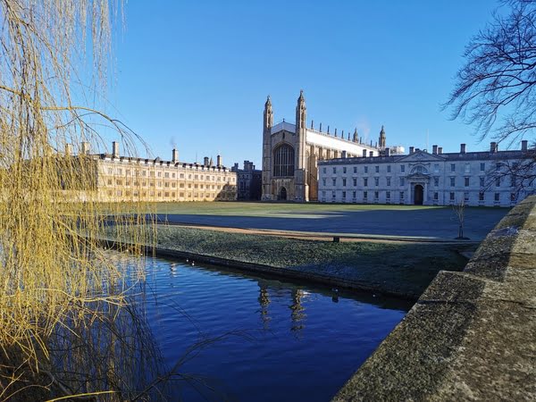 Die King’s College Chapel in Cambridge bei Sonnenschen von der brücke fotografiert mit blauen Wasser der Cam