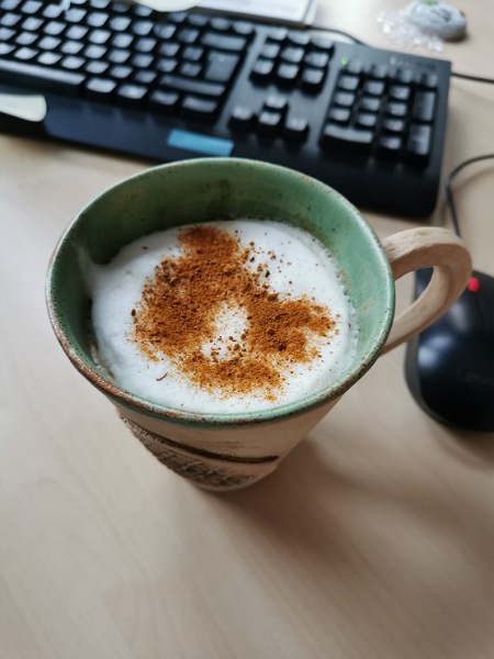 Kaffeetasse am Schreibtisch mit Milchschaum und arabische Mischung