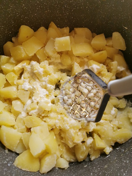 Gekochte Kartoffeln werden mit Milch und Butter gestampft.